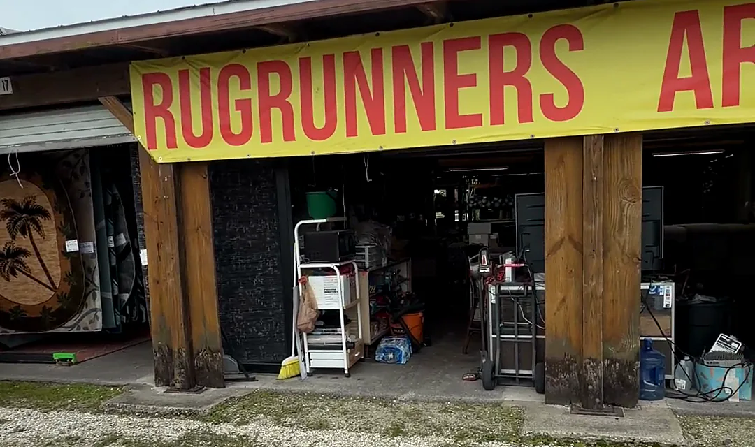 Shop frontage under a long yellow banner reading RUGRUNNERS in red letters, with open bays and wooden posts.